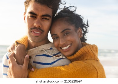 Portrait of smiling biracial couple embracing while enjoying sunny day at beach. lifestyle, love and weekend. - Powered by Shutterstock