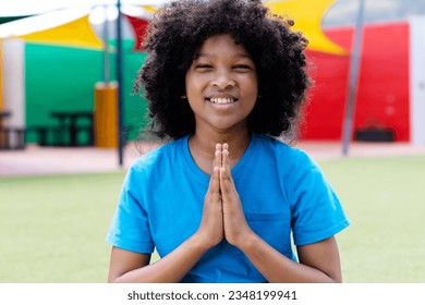Portrait of smiling biracial schoolgirl practicing yoga meditation in schoolyard, with copy space. Eeducation, childhood, elementary school, inclusivity, health and learning concept. - Powered by Shutterstock