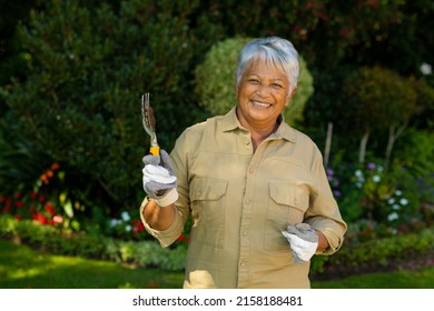 Portrait of smiling biracial senior woman with short hair wearing gloves and holding gardening fork. yard, plant, happy, unaltered, lifestyle, gardening, nature and retirement concept. - Powered by Shutterstock