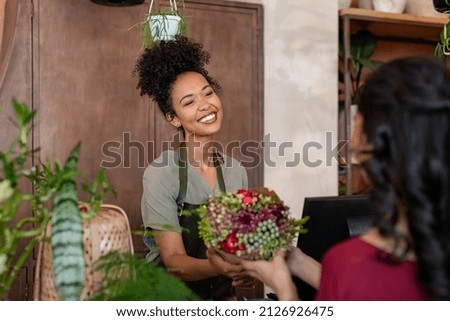 Happy florist selling bouquet to customer in flower shop