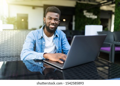 Portrait of a smiling black businessman with laptop at cafe - Shutterstock ID 1542585893