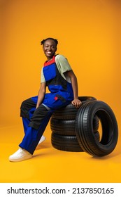 Portrait of smiling black female mechanic posing with new car tyres in studio - Shutterstock ID 2137850165