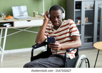 Portrait Of Smiling Black Man With Disability Listening To Music And Using Phone In Modern Home, Copy Space