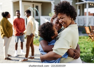 Portrait of smiling black woman embracing two sons at family gathering outdoors, copy space - Shutterstock ID 2213335559