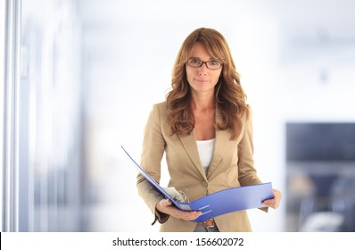 Portrait of smiling blond mature business woman standing in office.