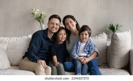 Portrait of smiling bonding loving young Hispanic latin parents and small cute kids siblings sitting on sofa, happy married couple posing at home with little son and daughter, relations concept. - Powered by Shutterstock