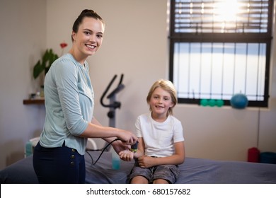 Portrait of smiling boy with female therapist scanning wrist at hospital ward - Powered by Shutterstock