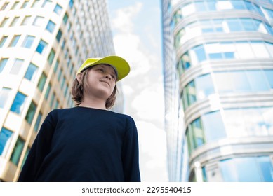 portrait of a smiling boy in a satin cap, black jacket on a sunny day in the business center, metropolis, outside - Shutterstock ID 2295540415