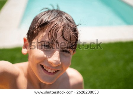 Portrait of smiling boy with wet hair by the poolside enjoying summer vacation with copy space