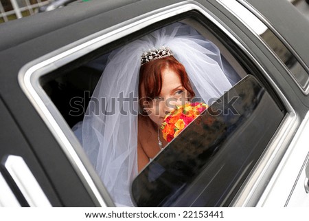 Portrait of smiling bride holding bouquer in wedding car limousine.