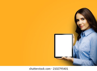 Portrait Of Smiling Brunette Businesswoman Showing Tablet Pc, Ipad Touchpad, With Copy Space For Text, Isolated Over Yellow Colour Background. Confident Beautiful Business Woman At Studio