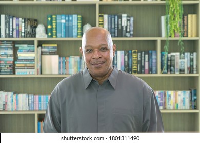 Portrait of smiling business senior old elderly black man, African American person working from home and talking to his colleagues in webcam group video call conference online in library .