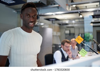 Portrait Of Smiling Businessman Standing By Glass Shield With Reminder Notes At Creative Office During Coronavirus