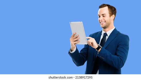 Portrait Of Smiling Businessman Using Tablet Pc, Touchpad, Ipad, Isolated Over Blue Color Background. Success In Business Studio Picture. Copy Space Text Area. App. Application Ad.