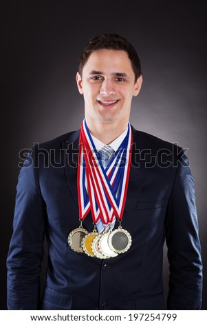 Portrait of smiling businessman wearing medals against black background