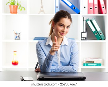 Portrait of smiling businesswoman loan agency expert showing thumb up. Amiable female manager sitting at the desk with laptop and phone.   - Shutterstock ID 259357667