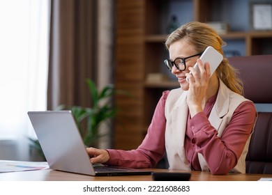 Portrait Of Smiling Businesswoman Talking On The Phone Using Laptop In Office Interior. Female Office Worker Searching New Clients, Negotiates With Business Partners, Looking For New Investors