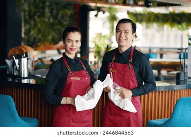 Portrait of smiling cafe waiters cleaning glassware before event - Powered by Shutterstock