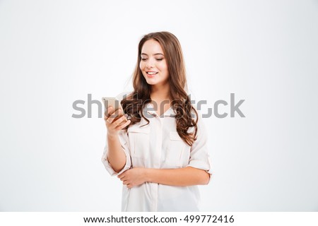 Portrait of a smiling casual woman holding smartphone over white background