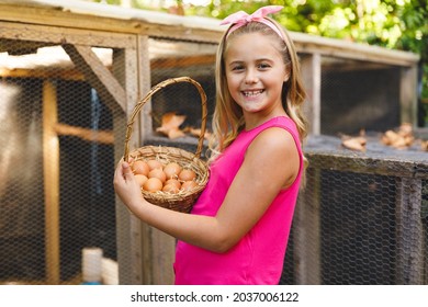 Portrait of smiling caucasian girl collecting eggs from hen house in garden. self sufficiency and spending time at home. - Powered by Shutterstock