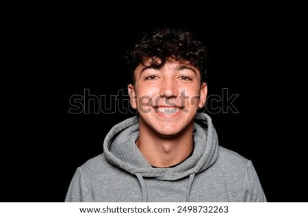 Portrait of a smiling Caucasian man in his 20s wearing a sweatshirt against a dark background.