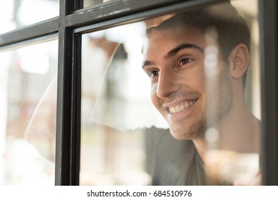 Portrait Of Smiling Caucasian Man Looking Away Through Glass Door