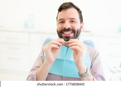 Portrait Of Smiling Caucasian Mid Adult Man Holding Clear Orthodontic Retainer