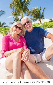 Portrait Of Smiling Caucasian Senior Couple In Colourful Clothes Carefree Outdoors By The Ocean At Tropical Beach Resort 