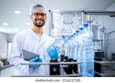 Portrait of smiling caucasian technologist expert with tablet computer standing by automated machine for PET water production in bottling factory. - Powered by Shutterstock