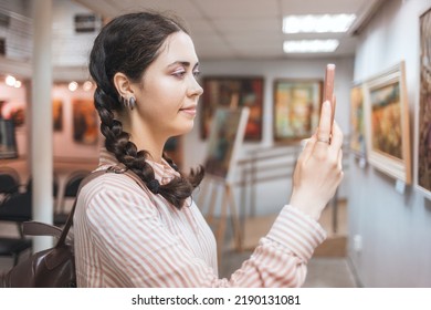 Portrait Of Smiling Caucasian Woman Using A Smartphone. Virtual Excursion With Audio Guide In The Art Gallery. Exhibition And Visit To The Museum.