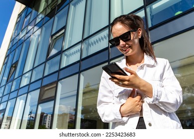 Portrait of smiling caucasian woman with white teeth chatting on phone searching information typing message, hold mobile device. Perfect healthy smile with veneer. Dental care. 

 - Shutterstock ID 2253423683