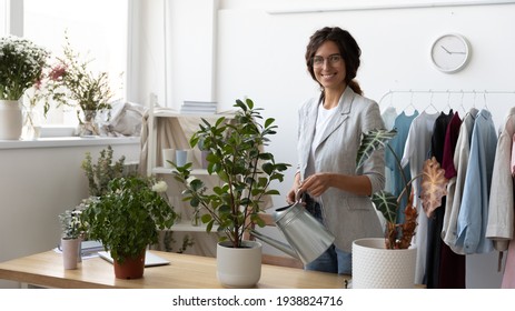 Portrait of smiling Caucasian young female florist or gardener water green house plants at workplace. Happy woman hold can pot take care of domestic flowers, enrich ground soil. Gardening concept. - Powered by Shutterstock