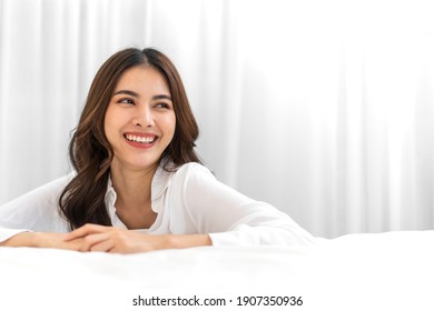Portrait of smiling cheerful beautiful pretty asian woman clean fresh healthy white skin posing in pajamas white clothes.Girl felling relaxing and enjoy time on the bed at home.asia beauty