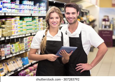 Portrait of smiling colleagues using a digital tablet at supermarket - Powered by Shutterstock