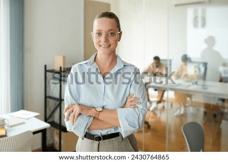 Portrait of smiling confident female entrepreneur standing in office of her company