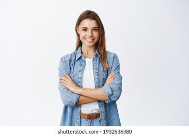 Porträt von einer lächelnden selbstbewussten Frau, die sich bereit und entschlossen fühlt, Querarme auf der Brust, selbstsicher, die Kamera auf weißem Hintergrund ansehen