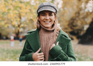 Portrait of a smiling confident woman in warm clothing looking at camera in city park. Fashionable, lovely blonde wearing her favorite fall collection. - Powered by Shutterstock