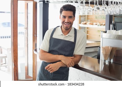 Portrait of a smiling confident young waiter standing at the cafe counter - Powered by Shutterstock