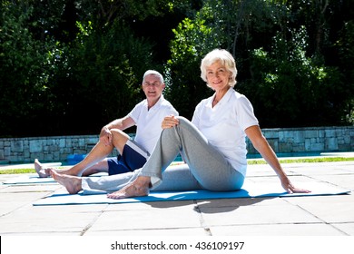 Portrait of smiling couple on exercise mat at poolside - Powered by Shutterstock