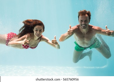 Portrait of smiling couple showing thumbs up while swimming underwater - Powered by Shutterstock