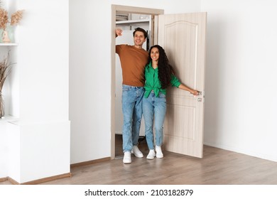 Portrait of smiling couple walking in their apartment, entering new home, happy cheerful young guy and lady standing in doorway of modern flat, looking at design interior together, coming inside - Powered by Shutterstock