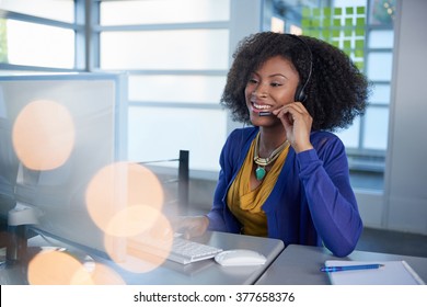 Portrait Of A Smiling Customer Service Representative With An Afro At The Computer Using Headset