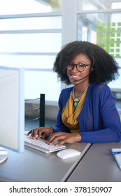 Portrait Of A Smiling Customer Service Representative With An Afro At The Computer Using Headset