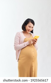 Portrait of a smiling cute pregnant woman using mobile phone isolated on a white background