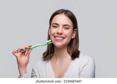 Portrait of a smiling cute woman holding toothbrush. Smiling woman with healthy beautiful teeth holding a toothbrush. Dental health background. Close up of perfect and healthy teeth with toothbrush.