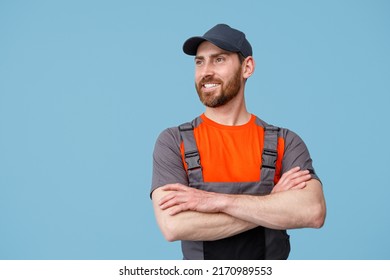 Portrait of smiling delivery man in uniform with crossed hands looking at side - Shutterstock ID 2170989553