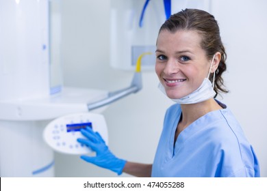 Portrait of smiling dental assistant adjusting x-ray equipment in dental clinic - Powered by Shutterstock