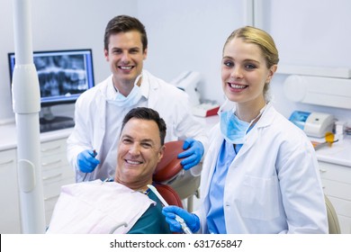 Portrait of smiling dentists and male patient in clinic