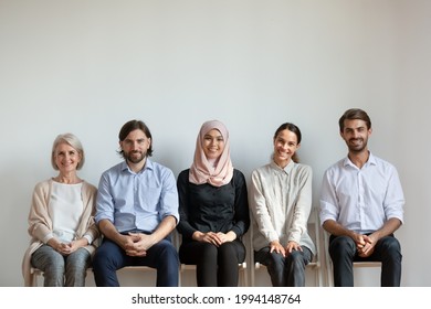 Portrait smiling diverse business people, multiethnic job applicants sitting on chairs in queue, row, waiting for job interview, looking at camera, staff, human resources and employment concept - Powered by Shutterstock