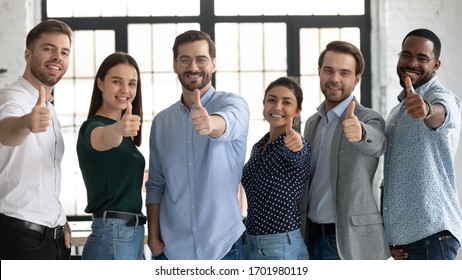 Portrait of smiling diverse multiracial businesspeople stand together show thumbs up recommending good company service, happy multiethnic colleagues give sincere recommendation of course or training - Powered by Shutterstock